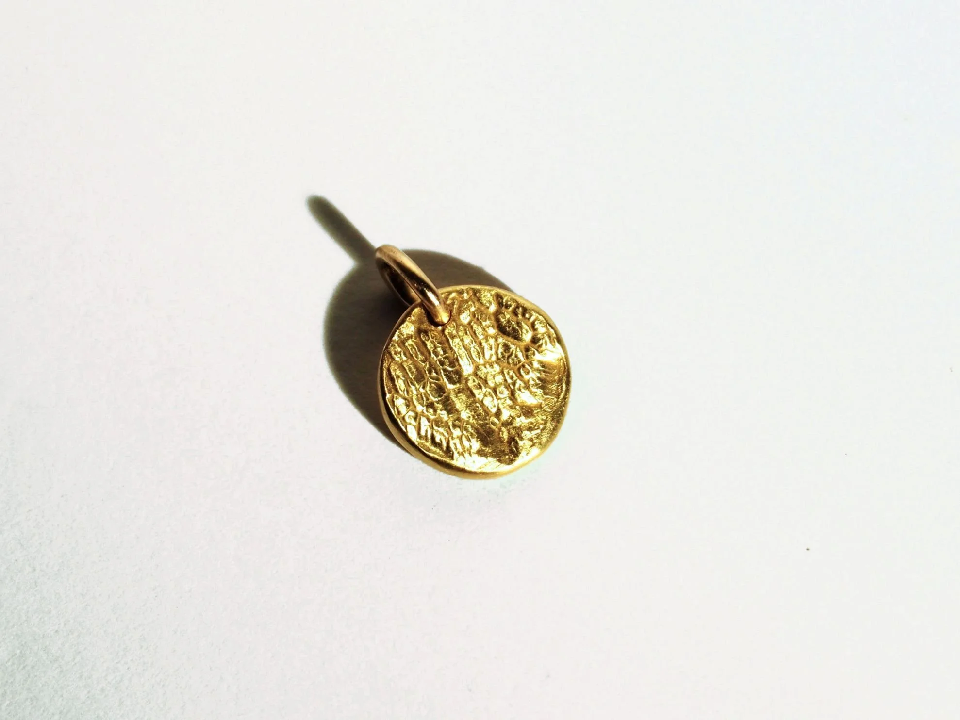 Collier empreinte de truffe de chien en or jaune sur fond blanc.