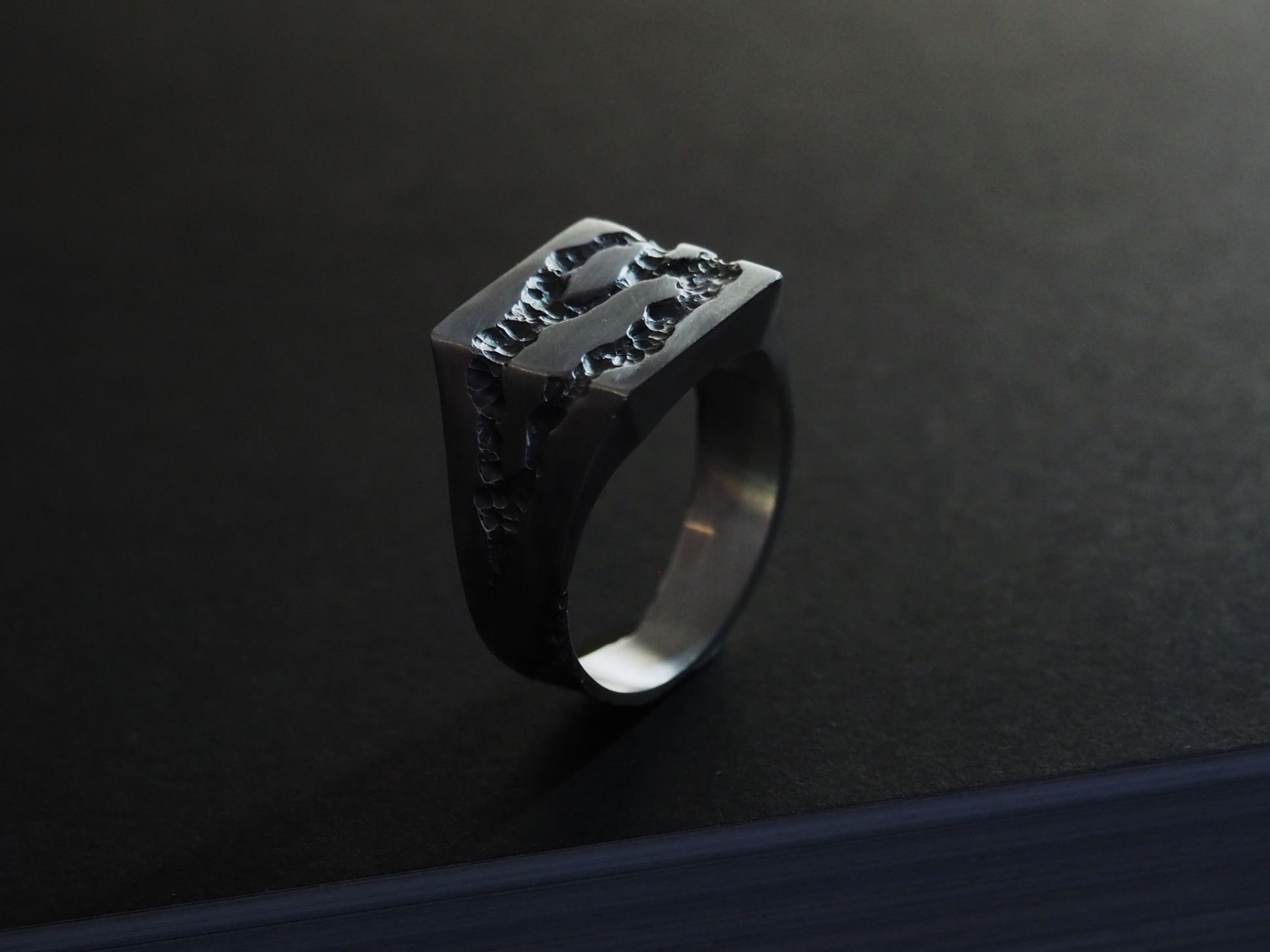 Chevalière sur mesure sur fond noir.