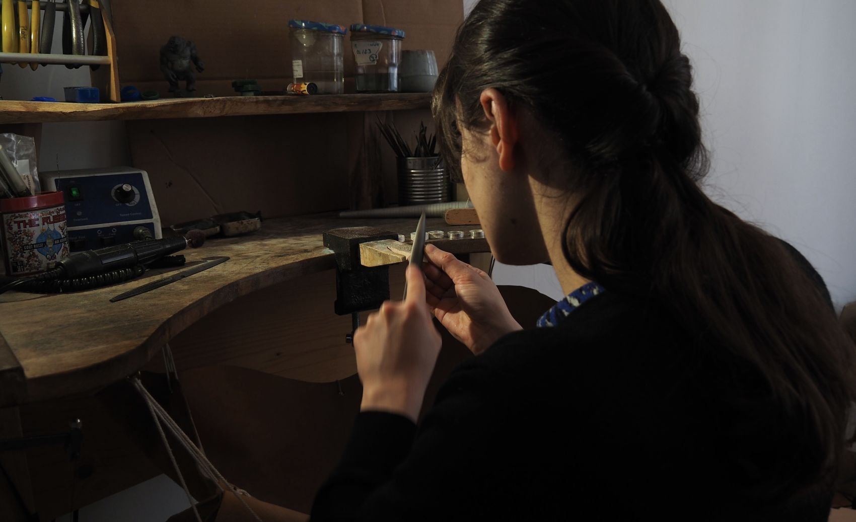 l’artisane bijoutière à son établi en train de fabriquer des bijoux truffe de chien. Après avoir récupéré le kit empreinte envoyé aux clients et mis l’empreinte de leur museau sur des colliers et bagues, elle reprend les fontes.