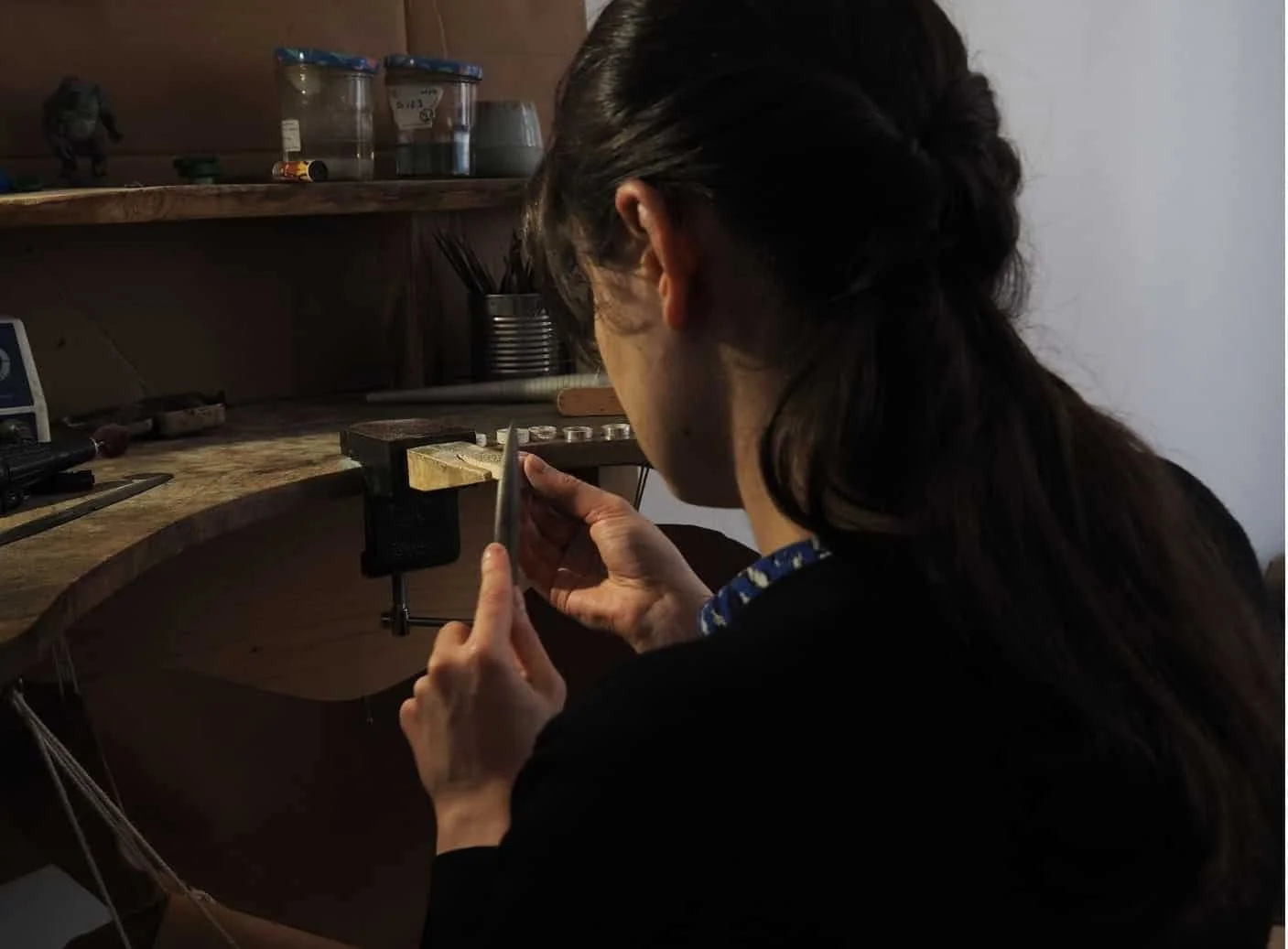 l’artisane bijoutière à son établi en train de fabriquer des bijoux truffe de chien. Après avoir récupéré le kit empreinte envoyé aux clients et mis l’empreinte de leur museau sur des colliers et bagues, elle reprend les fontes.