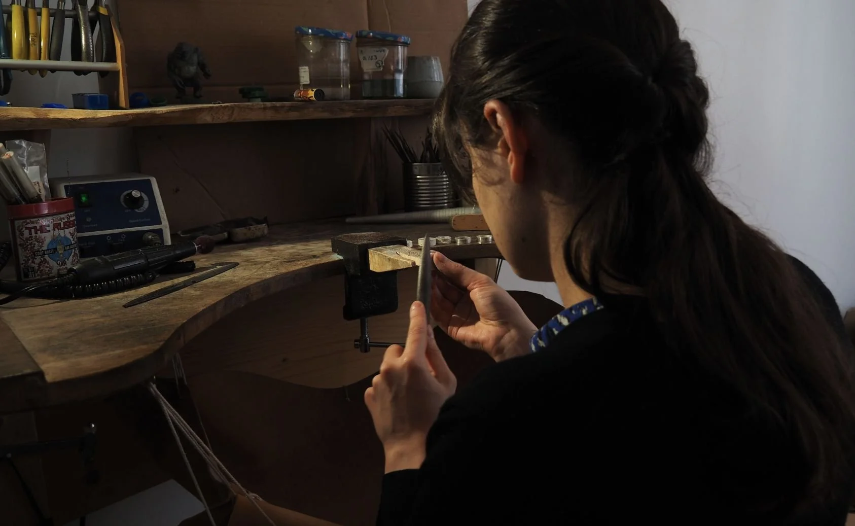 Artisane bijoutière lyonnaise qui travaille à son établi pour fabriquer des bijoux faits main.