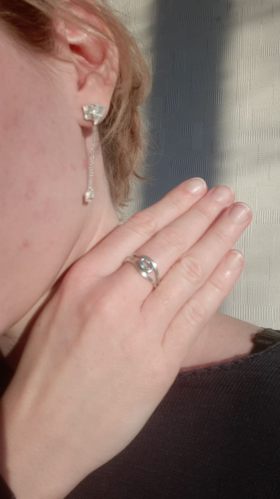 Femme élégante avec une boucle d’oreille et une bague sur-mesure en argent recyclé. Deux créations d’Atelier 962°, bijouterie artisanale lyonnaise mêlant textures mates et lignes contemporaines intemporelles.