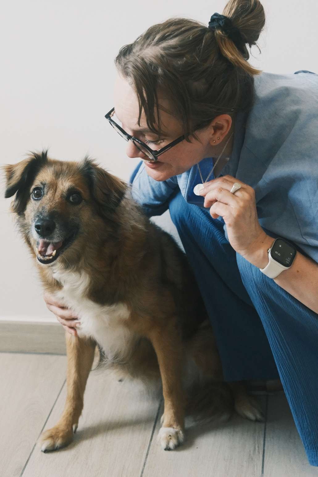 Femme qui tient dans sa main un collier empreinte truffe de chien et qui fait un câlin à son chien.