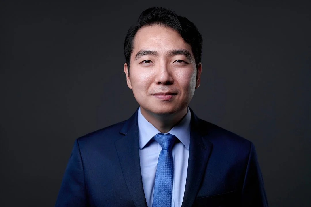 Headshot of an asian man wearing a blue suit and tie