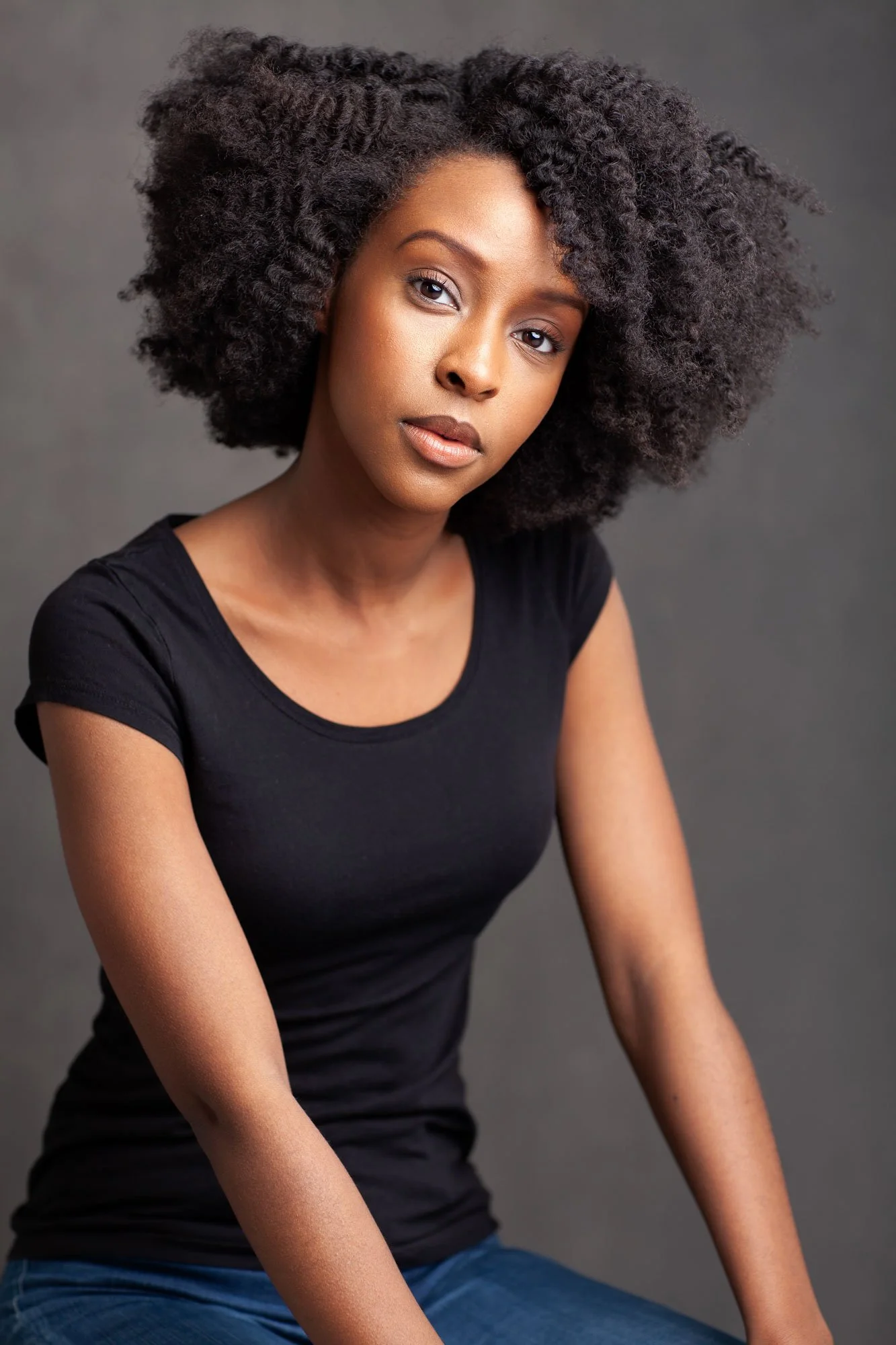 Actor headshot of actress Ebony Obsidian of Tyler Perry's Sistas, photographed in New York against a dark grey background, wearing a simple black t-shirt and with natural hair.