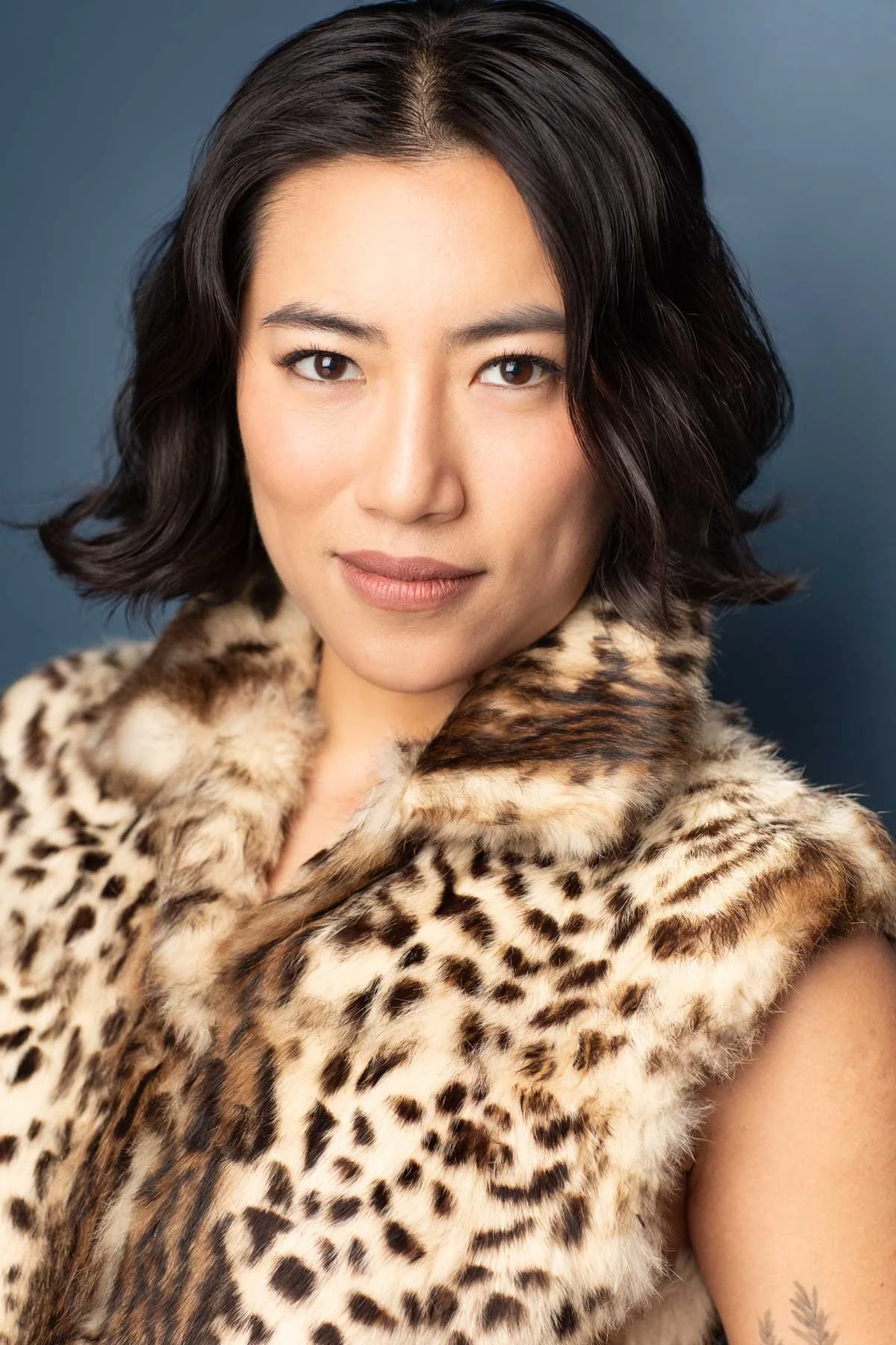 Legit actor headshot photographed in NYC by Hancock Headshots, Asian woman with bob against dark blue backdrop