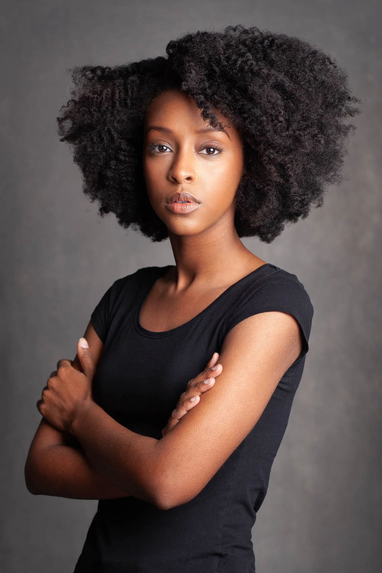 Actress Ebony Obsidian of Tyler Perry's Sistas acting headshot photographed in a Brooklyn studio wearing natural hair and a simple black t-shirt against a dark grey backdrop.