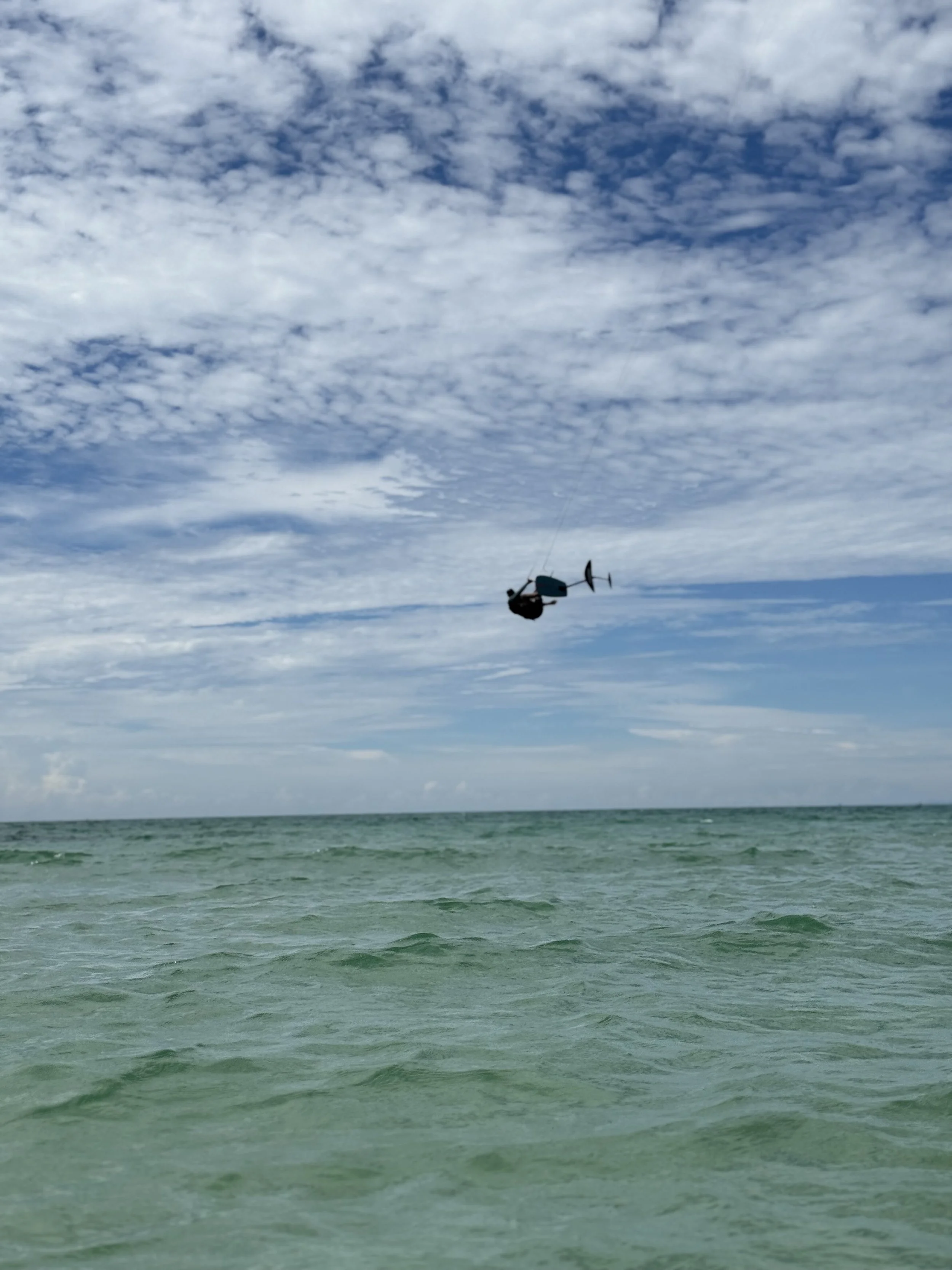 A helicopter flying above the ocean with a cloudy sky.