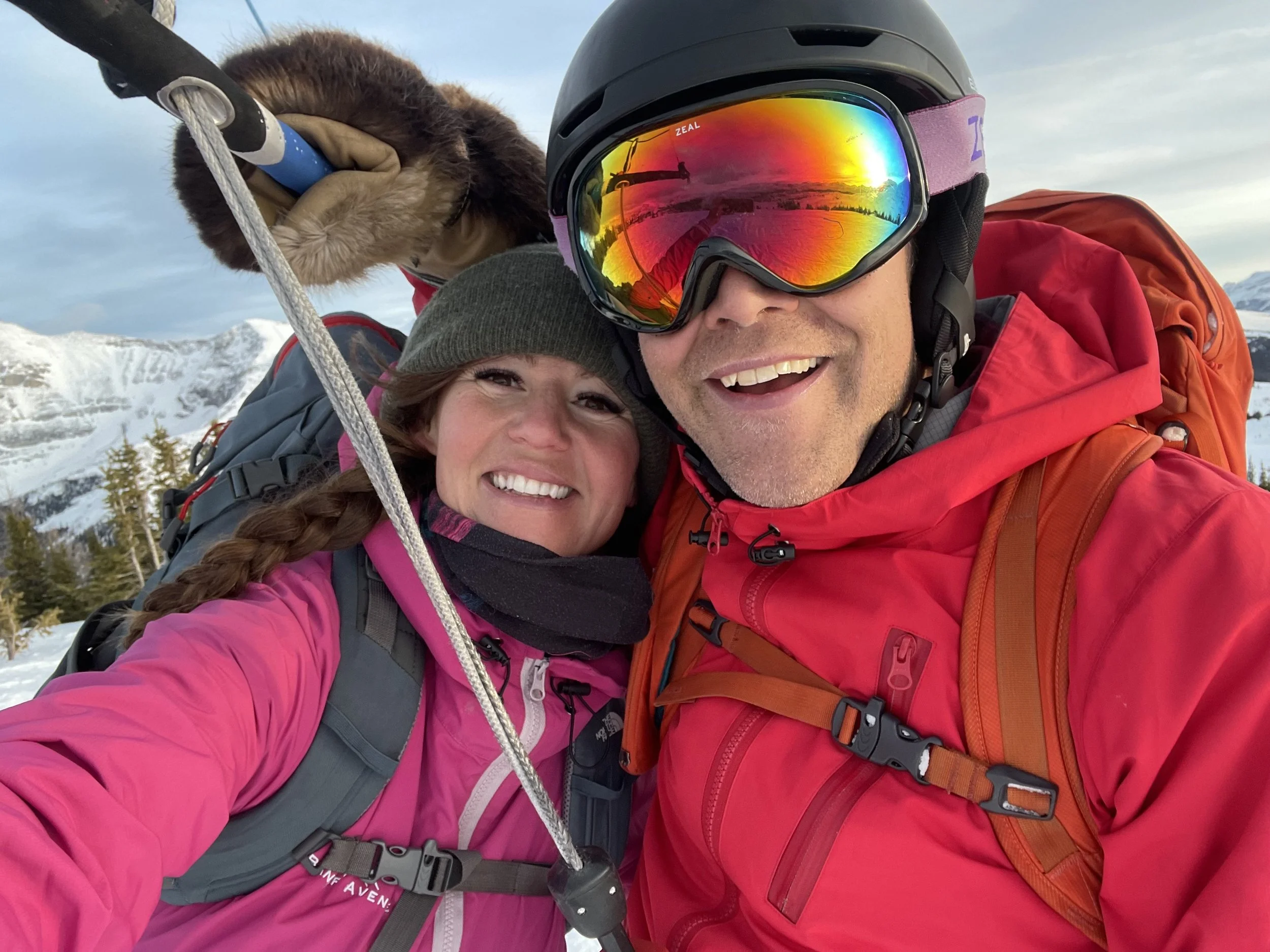 Guides Mar and Ryan in winter gear taking a selfie outdoors in a snowy mountain landscape, with sky and snow-covered peaks in the background. Sunshine Meadows. Sunshine Ski Resort. Wawa Chair. Wawa Mountain. Gin Shaman 3.1 flying. 