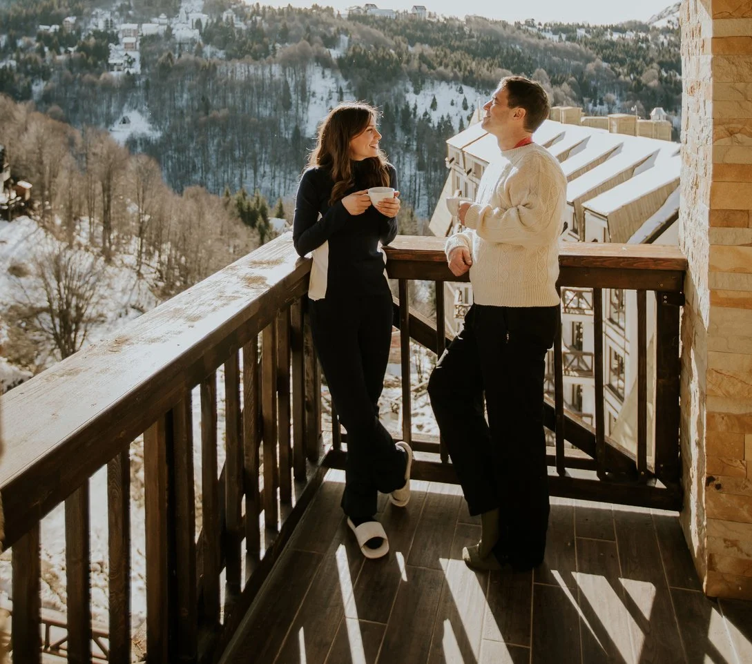 First responder and their spouse standing on a balcony outside in the winter having coffee.