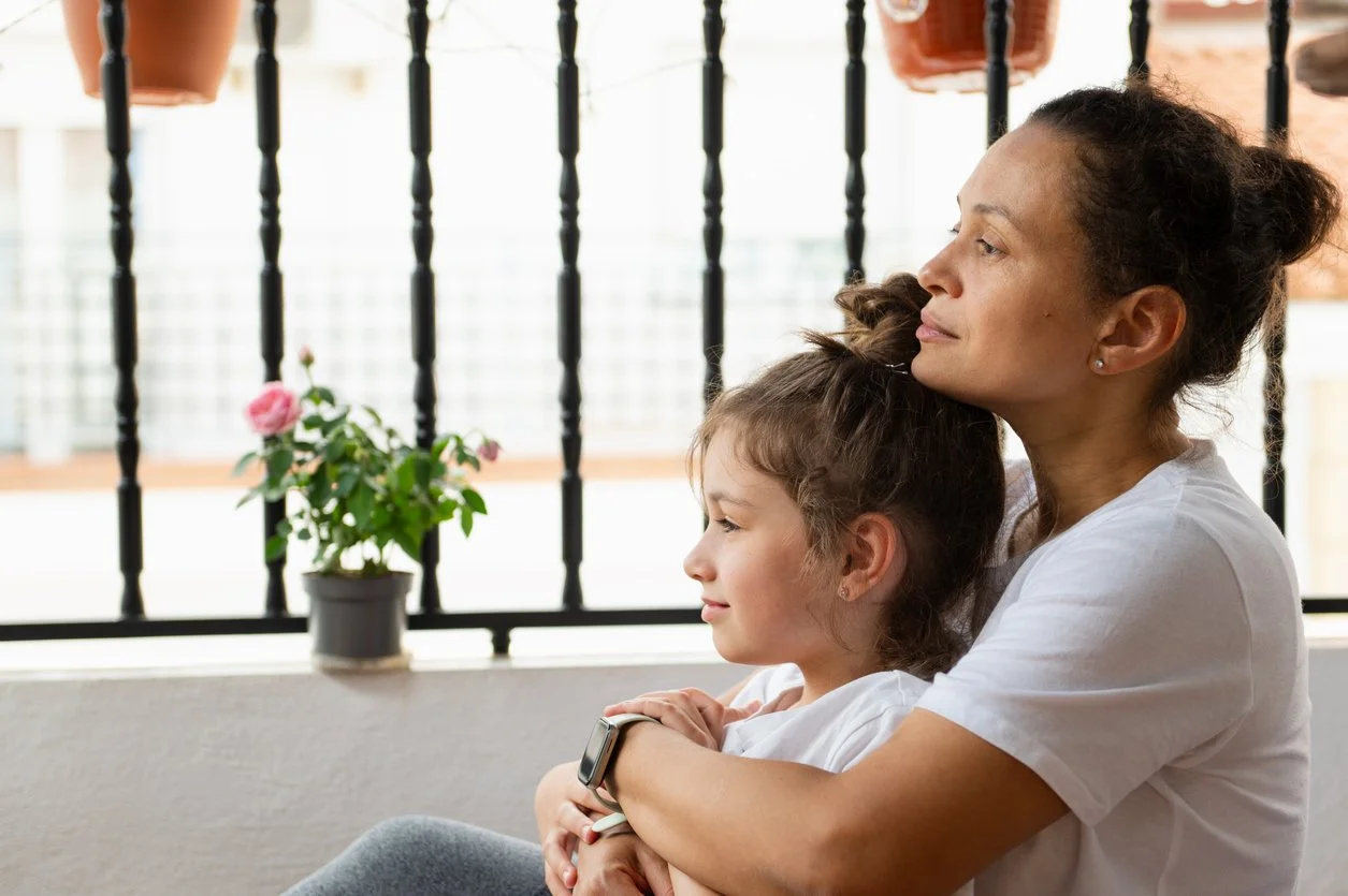 First responder mom sitting and holding her daughter while looking outside.