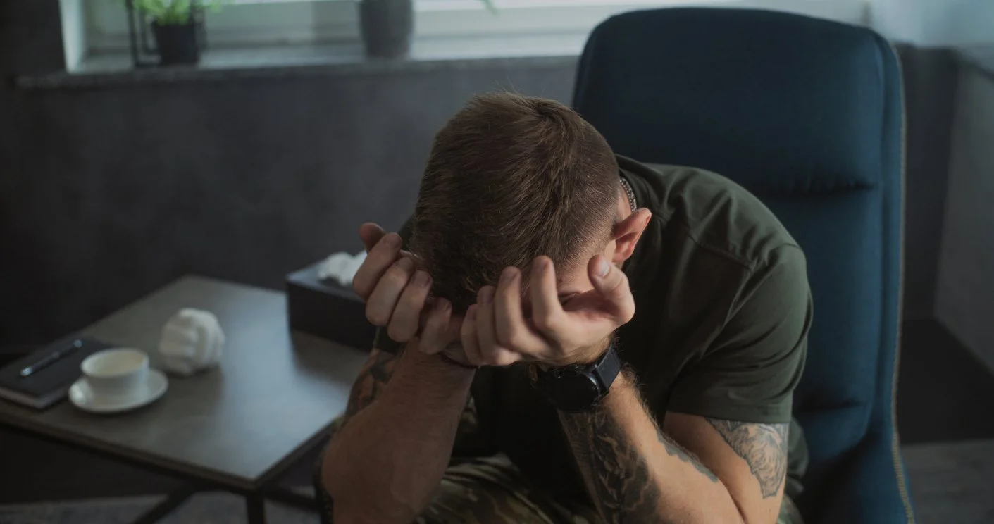 Male first responder sitting on a chair with his face in his hands.