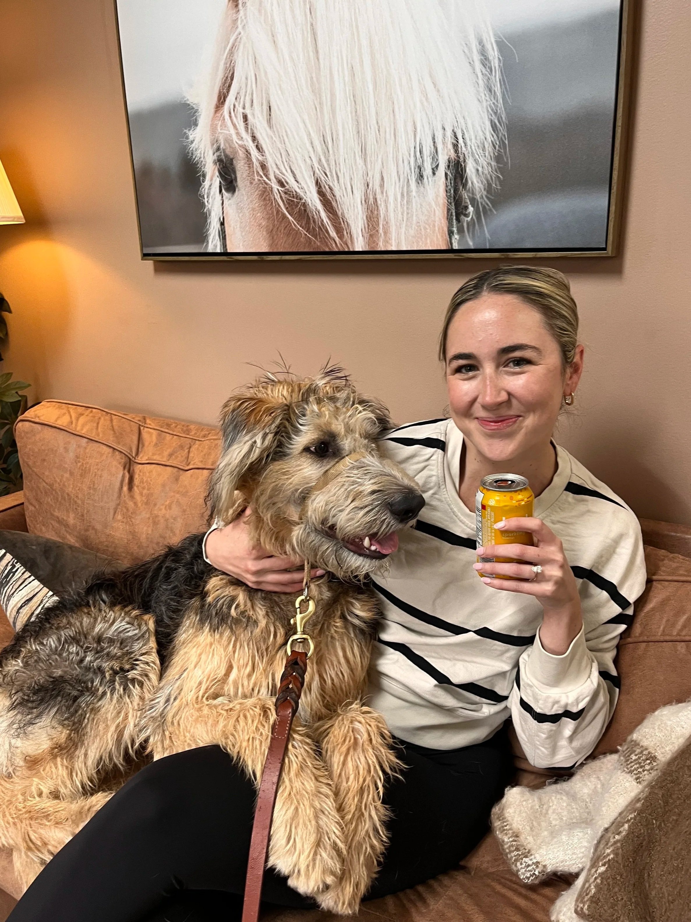 Peace of Mind CBT female client sitting on the couch at the clinic with River the Therapy Dog resting on her leg.