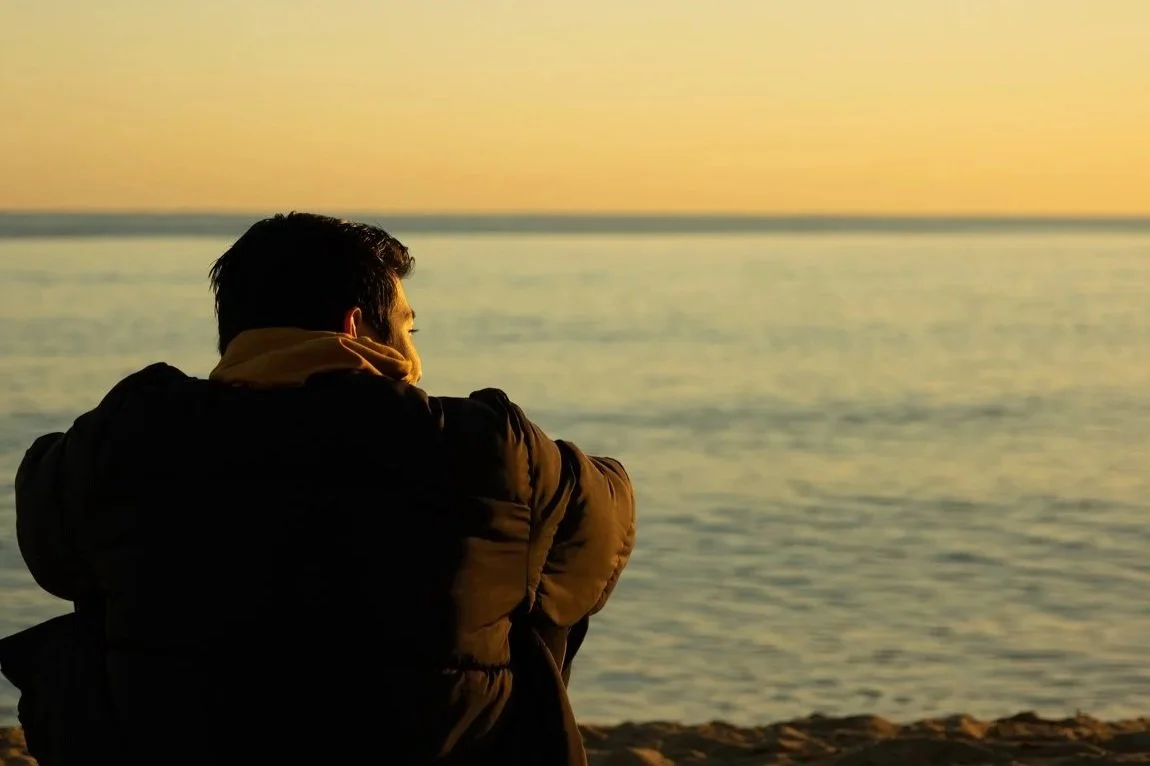 Man watching the sunrise over a lake as relief from Anxiety.