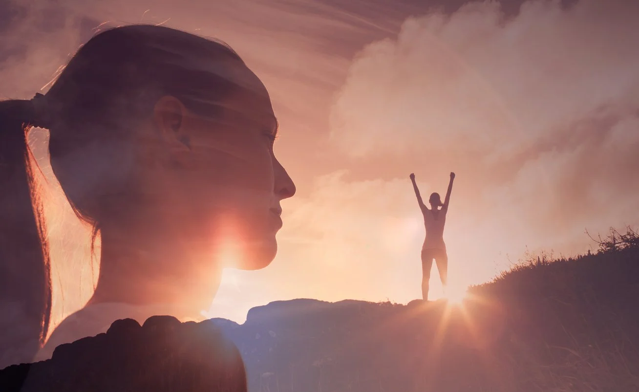 Woman in the background standing at the top of a mountain with her hands in the air and the same womans side profile is in the foreground with a look of pride for managing Depression.