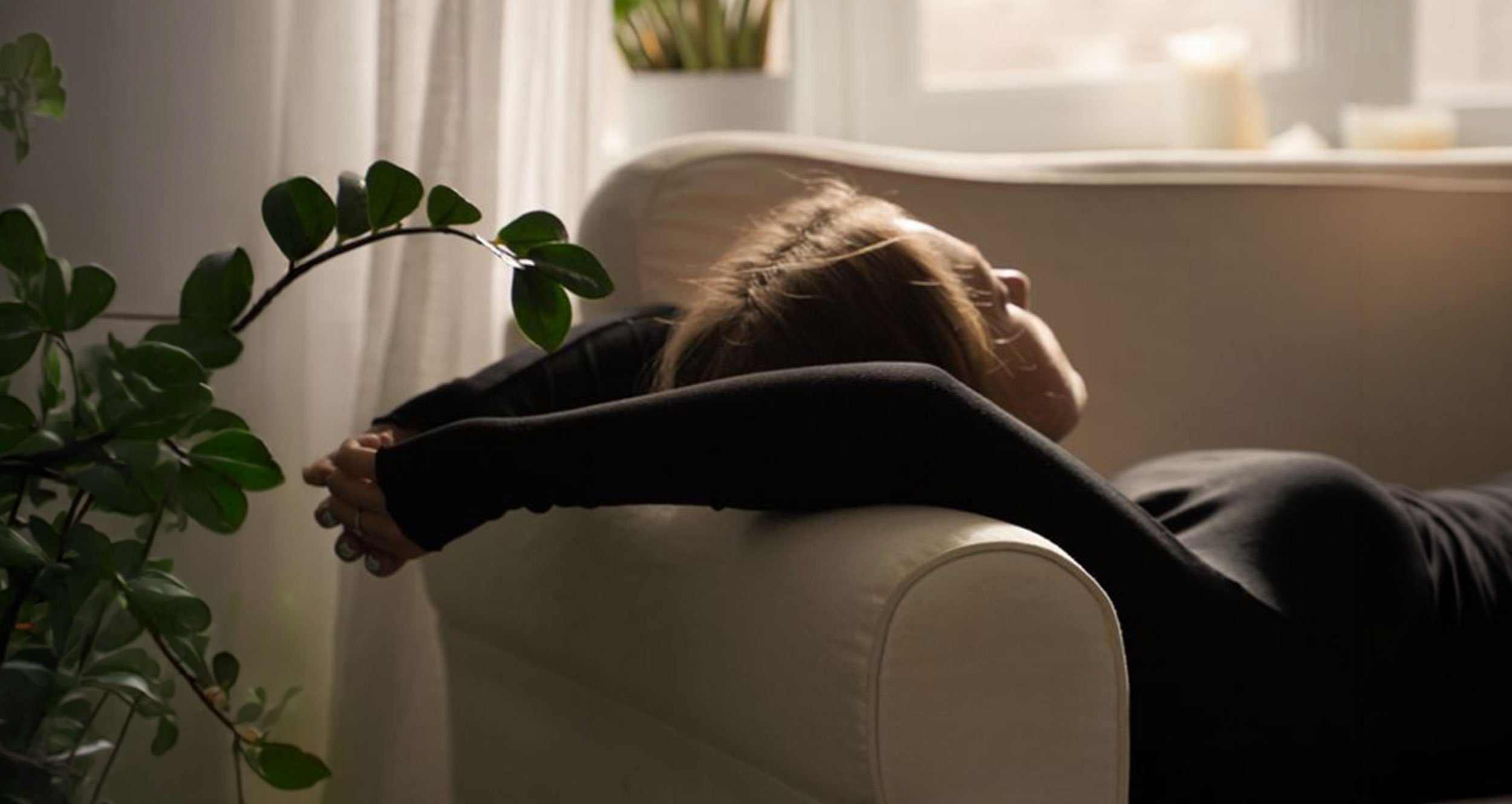Person resting over the arm of a sofa, illustrating the fatigue of Long COVID and post-viral recovery