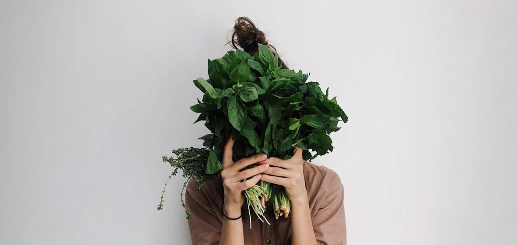 Person holding a large bunch of leafy greens, illustrating nutrition support for gut and digestive health