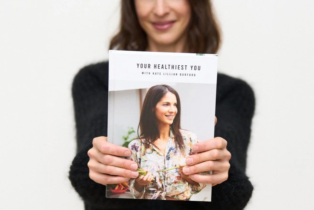 Kate Lillian Burford holding a copy of her Your Healthiest You Book
