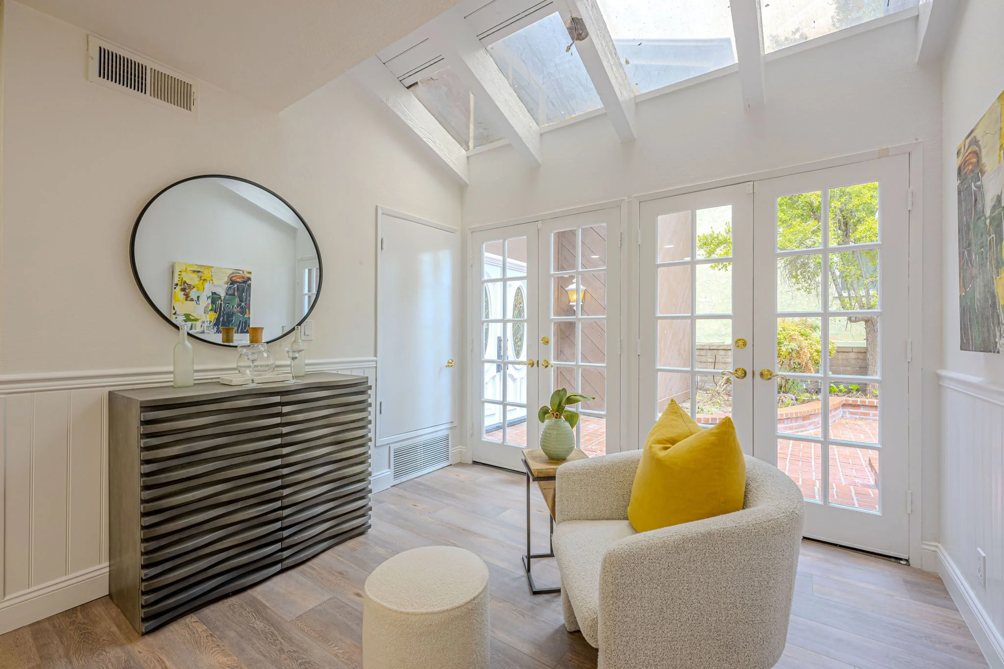 A single-family house with a brick exterior, two-car garage, front yard with grass, trees, and shrubs, and a clear blue sky.