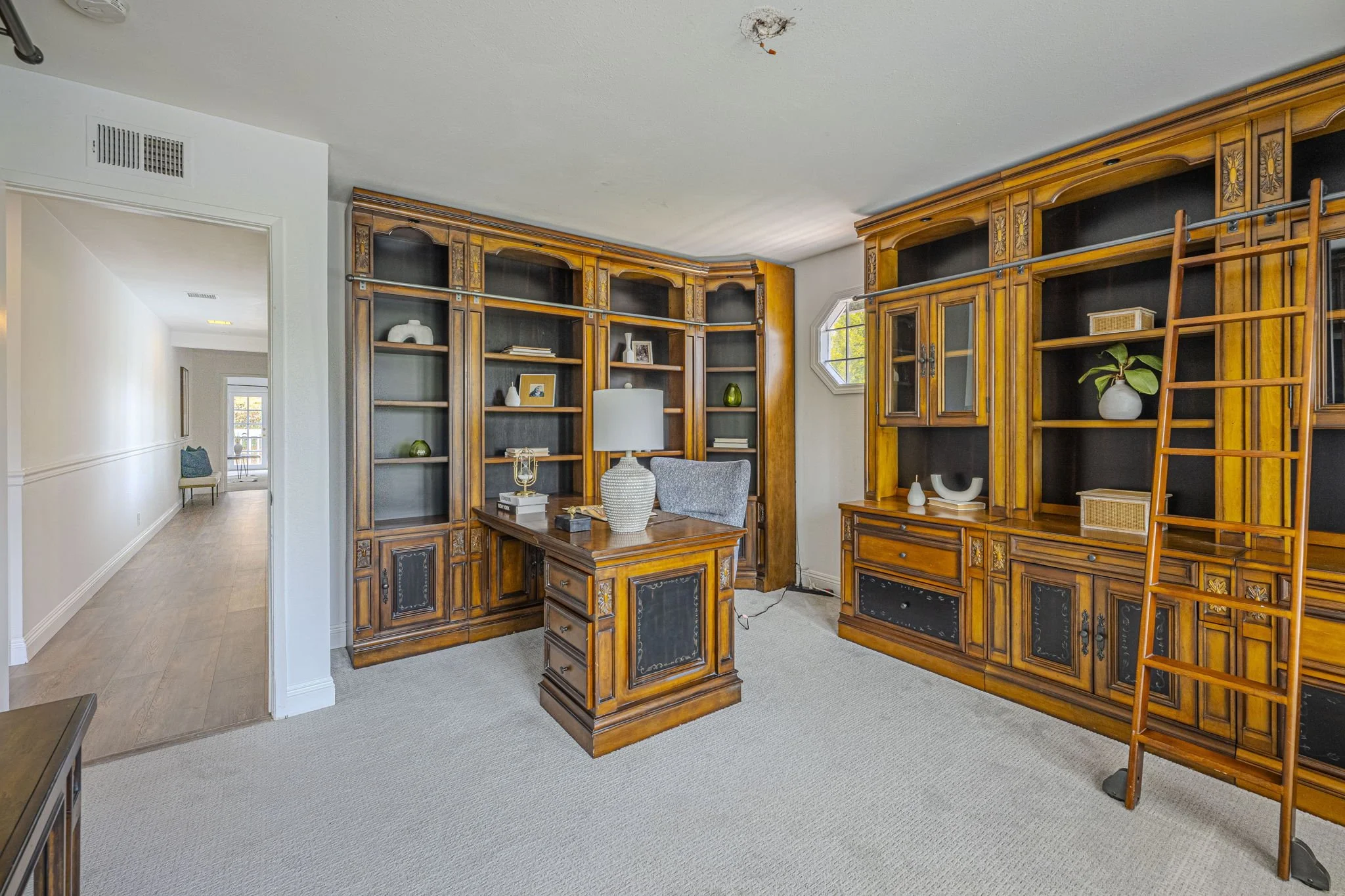 Indoor recreational room with a pool table, sitting area, and large windows with plants outside.