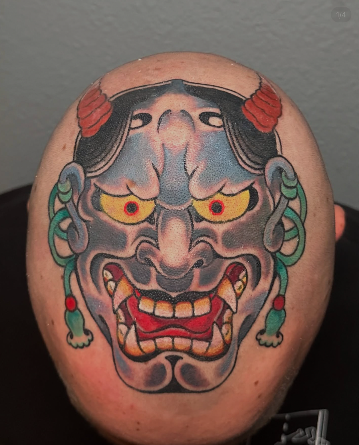Tattoo of a vampire-like woman with yellow eyes, fangs, red hair, and greenish-brown tentacle-like appendages around her face.
