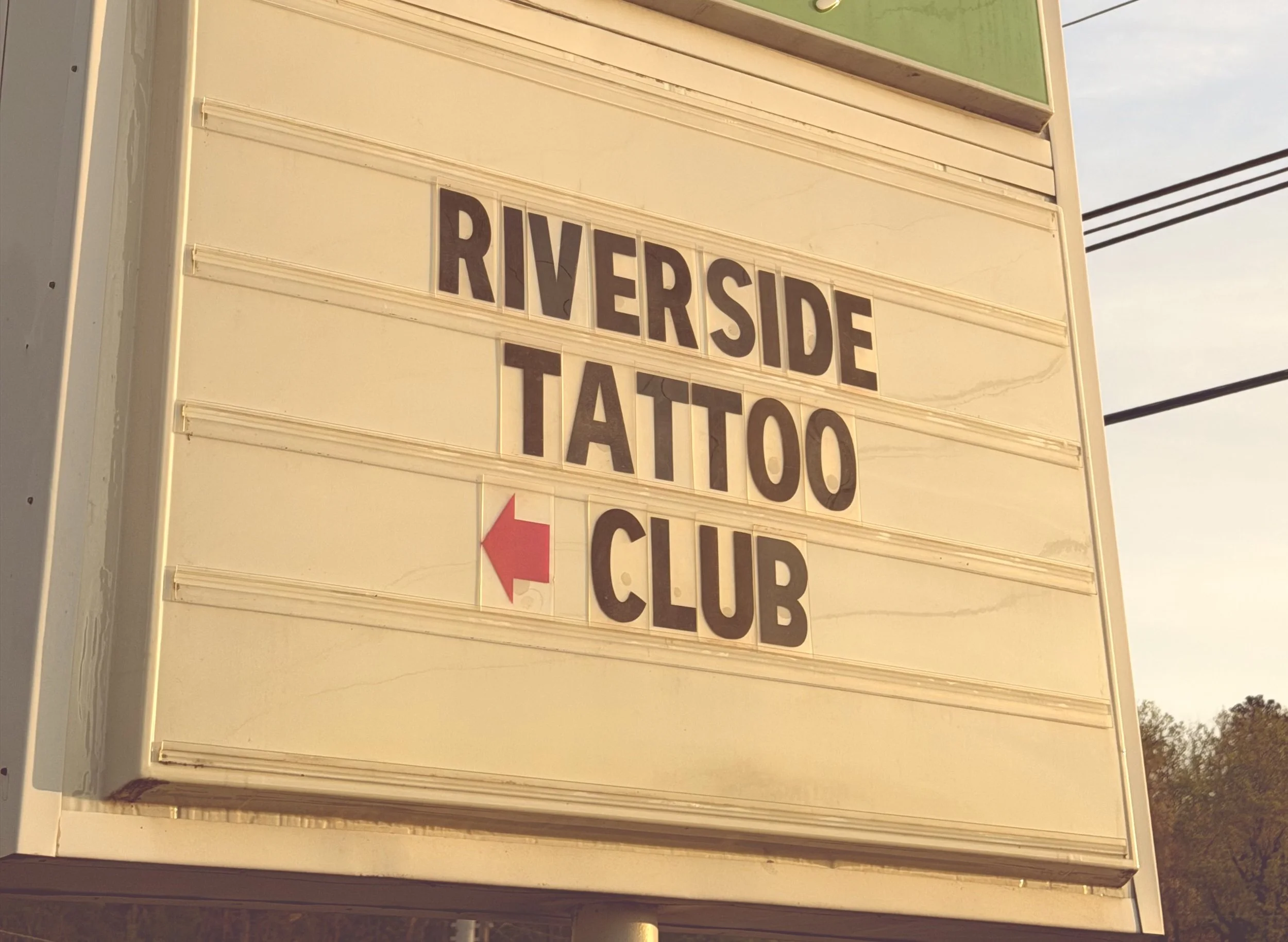 Riverside Tattoo Club marquee sign with a red arrow pointing to the shop on Chapman Highway in Knoxville, TN