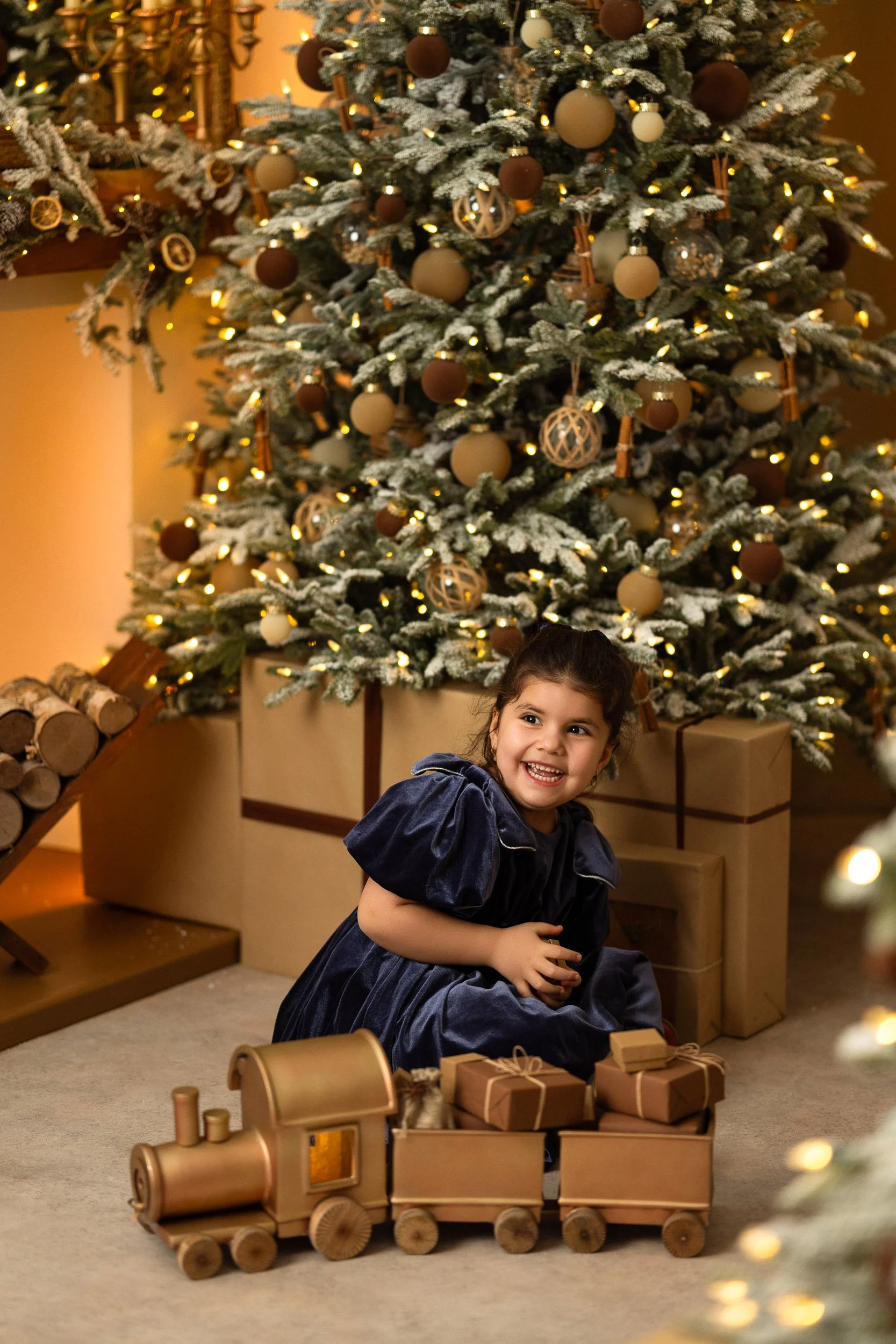 Child smiling while playing with the train in the Christmas set at Elberta Pictures.