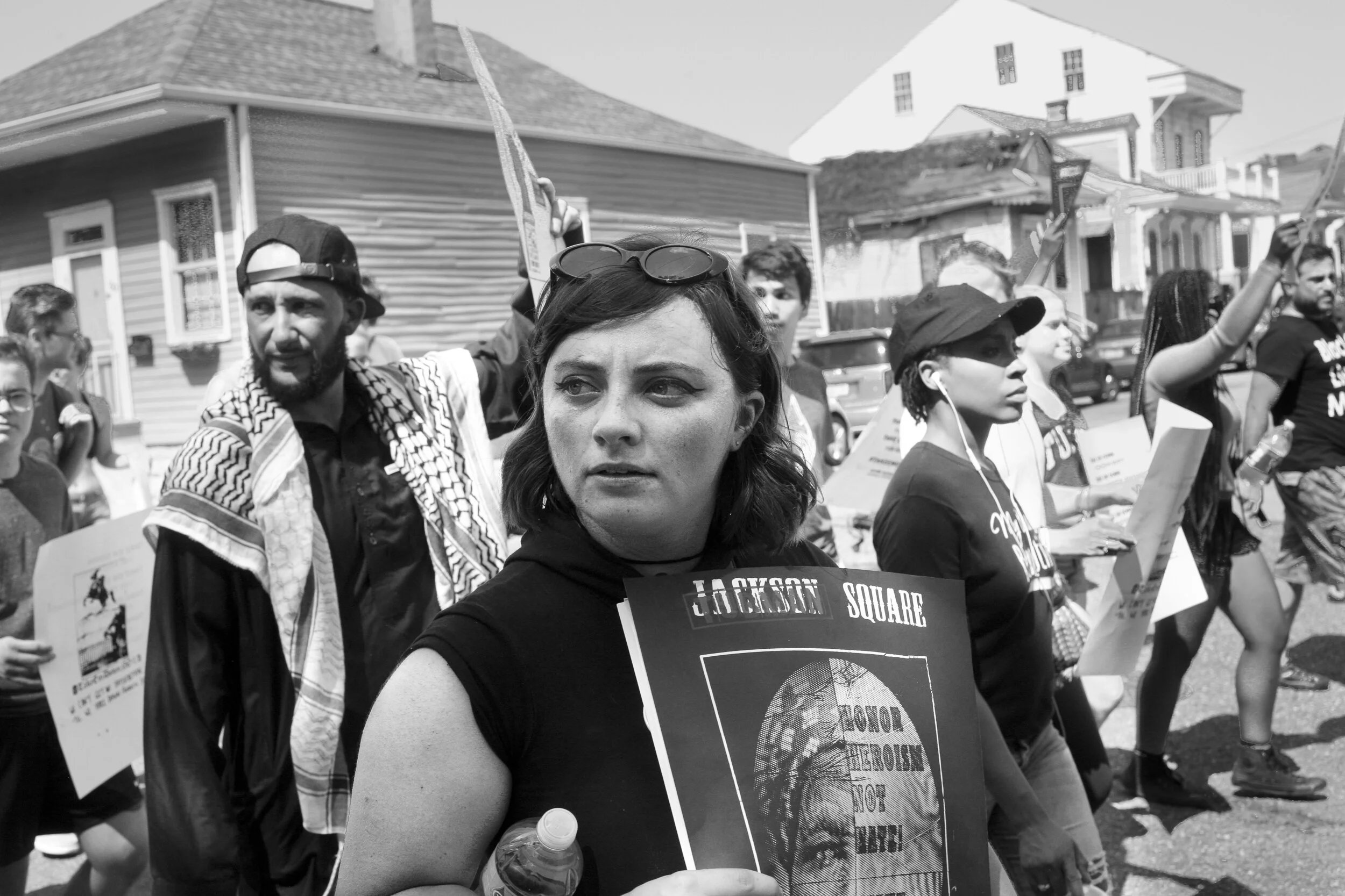 Woman participating in march for the removal of monuments to white supremacy, holding sign which overlays a picture of Harriet Tubman over Andrew Jackson