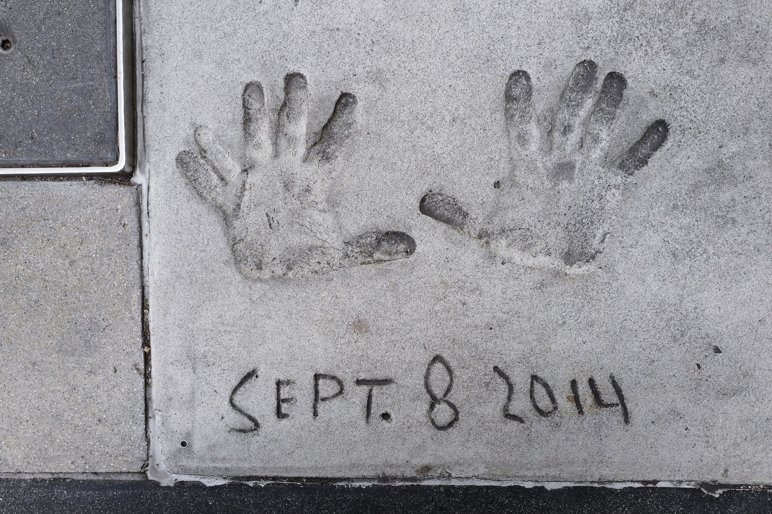 Concrete sidewalk with two handprint impressions and the date 'Sept. 8, 2014' written below.