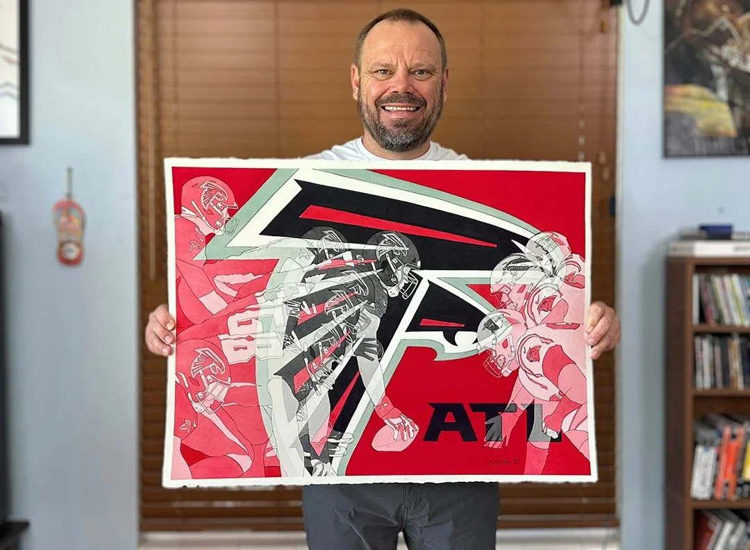 Sports Artist Alvin Fall displaying the completed 22" x 30" Falcons watercolor in his studio, demonstrating the scale of the piece and the bold contrast between the red backdrop and black falcon silhouette