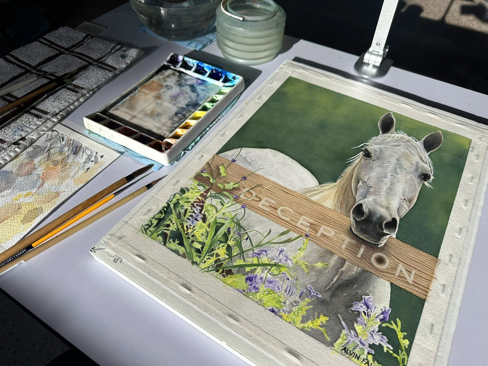Completed watercolor painting of Deception resting on the artist's desk alongside brushes and palette, ready for delivery.