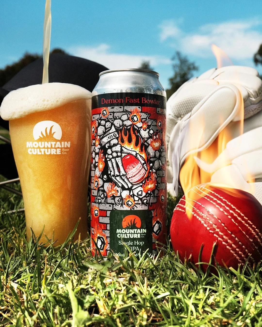 A can of Mountain Culture Single Hop IPA with a design featuring a cracked wall and fiery basketball, a glass of beer, a red football, and a white football glove on grass with a blue sky background.