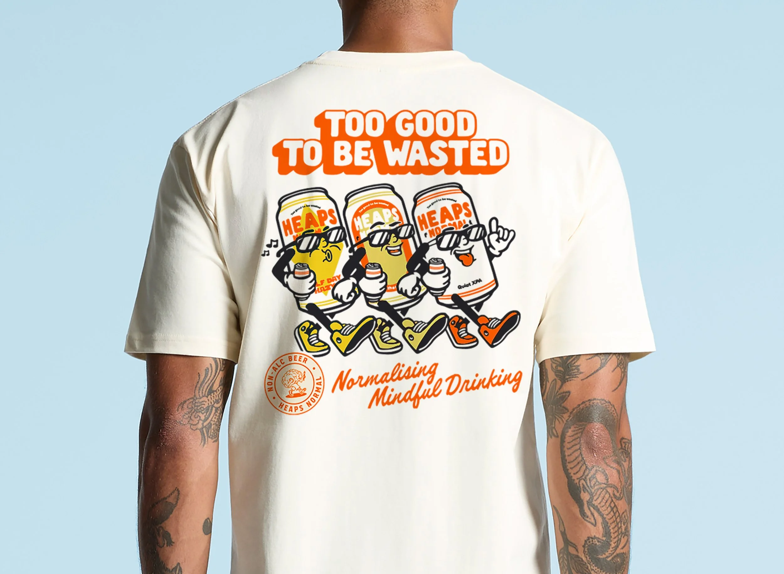 Back of a person wearing a cream-colored T-shirt with a graphic of animated soda cans, sunglasses, and sneakers, with the text 'Too good to be wasted' and 'Normalising mindful drinking' on the shirt.
