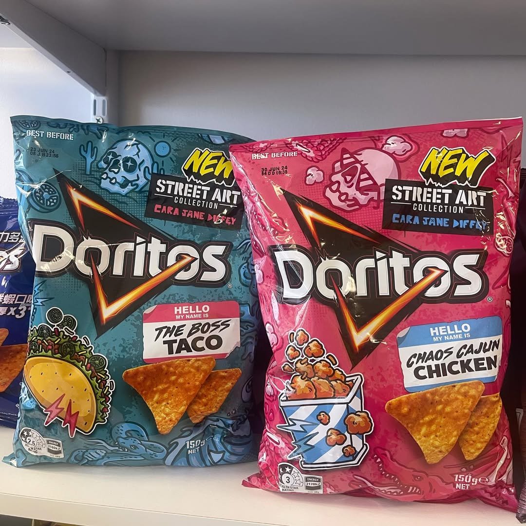 Two bags of Doritos chips, one blue and one pink, with street art collection branding. The blue bag character is called 'The Boss Taco' and the pink bag character is called 'Chaos Cajun Chicken'. Each bag has a flavor-themed illustration and a small 