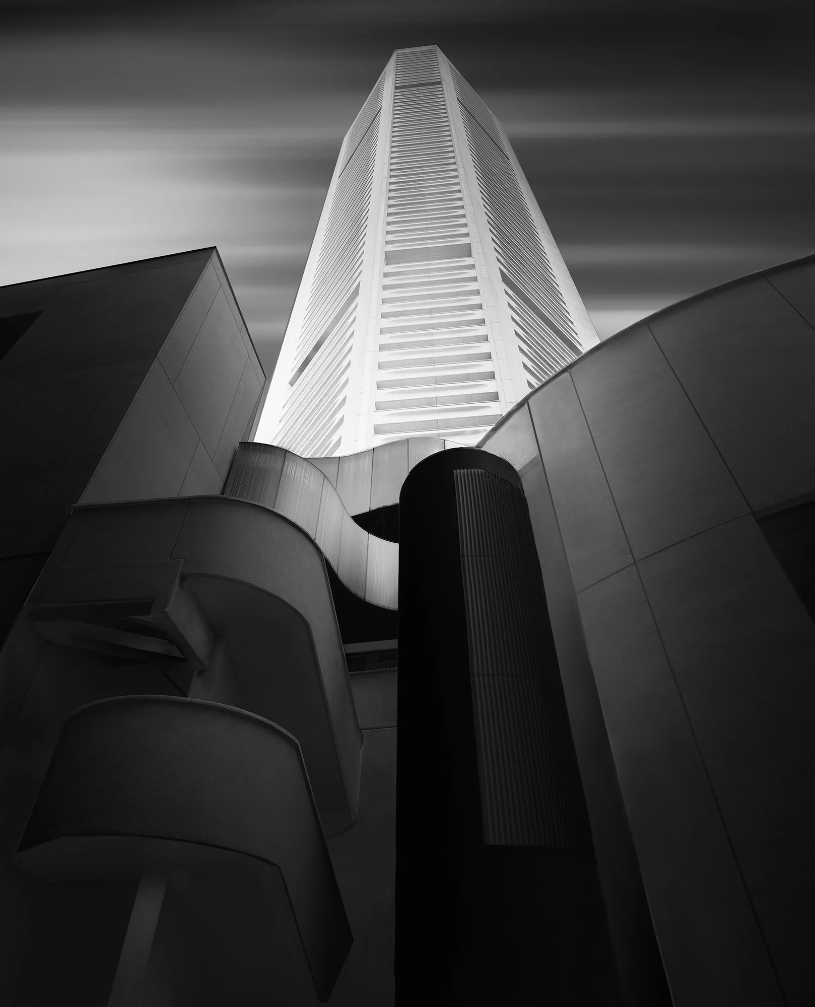 Black and white photo of a tall skyscraper viewed from the ground with a modern architectural base.