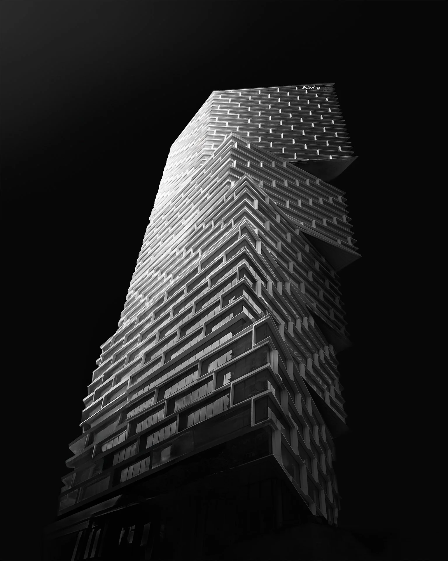 Low-angle view of a modern, multi-story skyscraper with a distinctive geometric design, against a black background.
