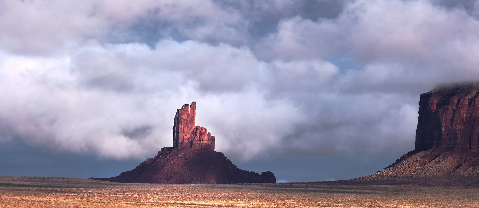 Hoodoos rock formations in a desert landscape with cloudy sky.
