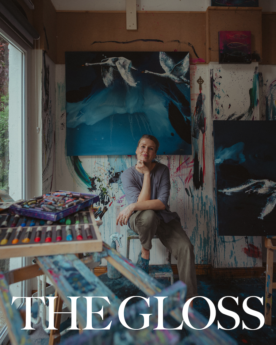 A woman sitting in an art studio, surrounded by abstract paintings and colorful art supplies, with the title "THE GLOSS" overlaid at the bottom.