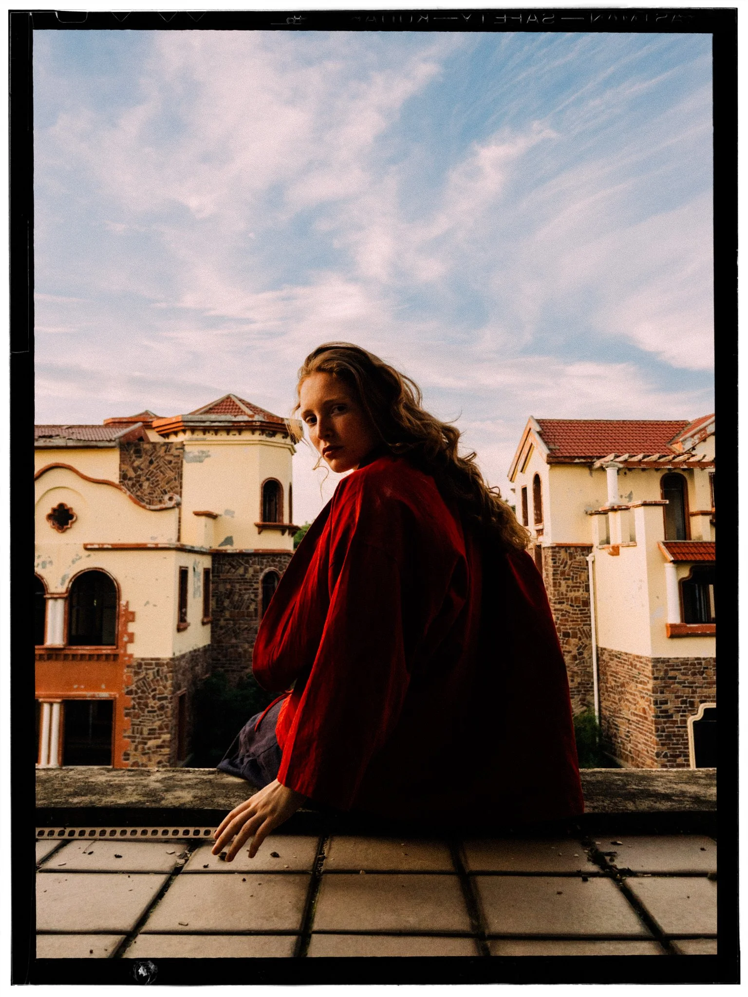 A beautiful redheaded dancer wearing red and looking over her shoulder into the camera in a building site in China