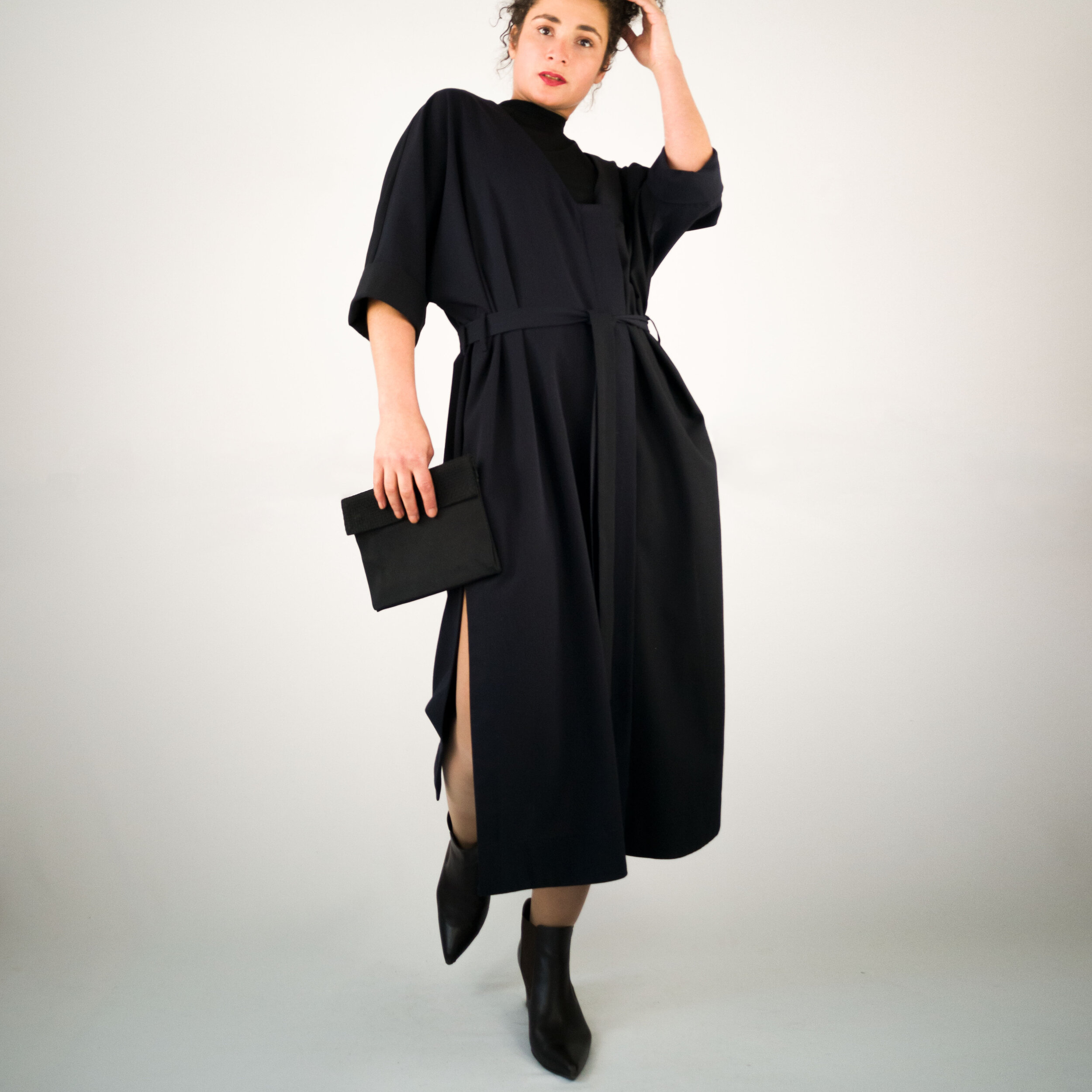 Langes Mantelkleid mit seitlichen Schlitzen und verdeckter Knopfleiste;Vorderansicht;mit Gürtel und Etui-Tasche;dunkelblau;Wollstoff;Taschen in der Naht;Steinnuss-Knöpfe;Slow Fashion made in Berlin