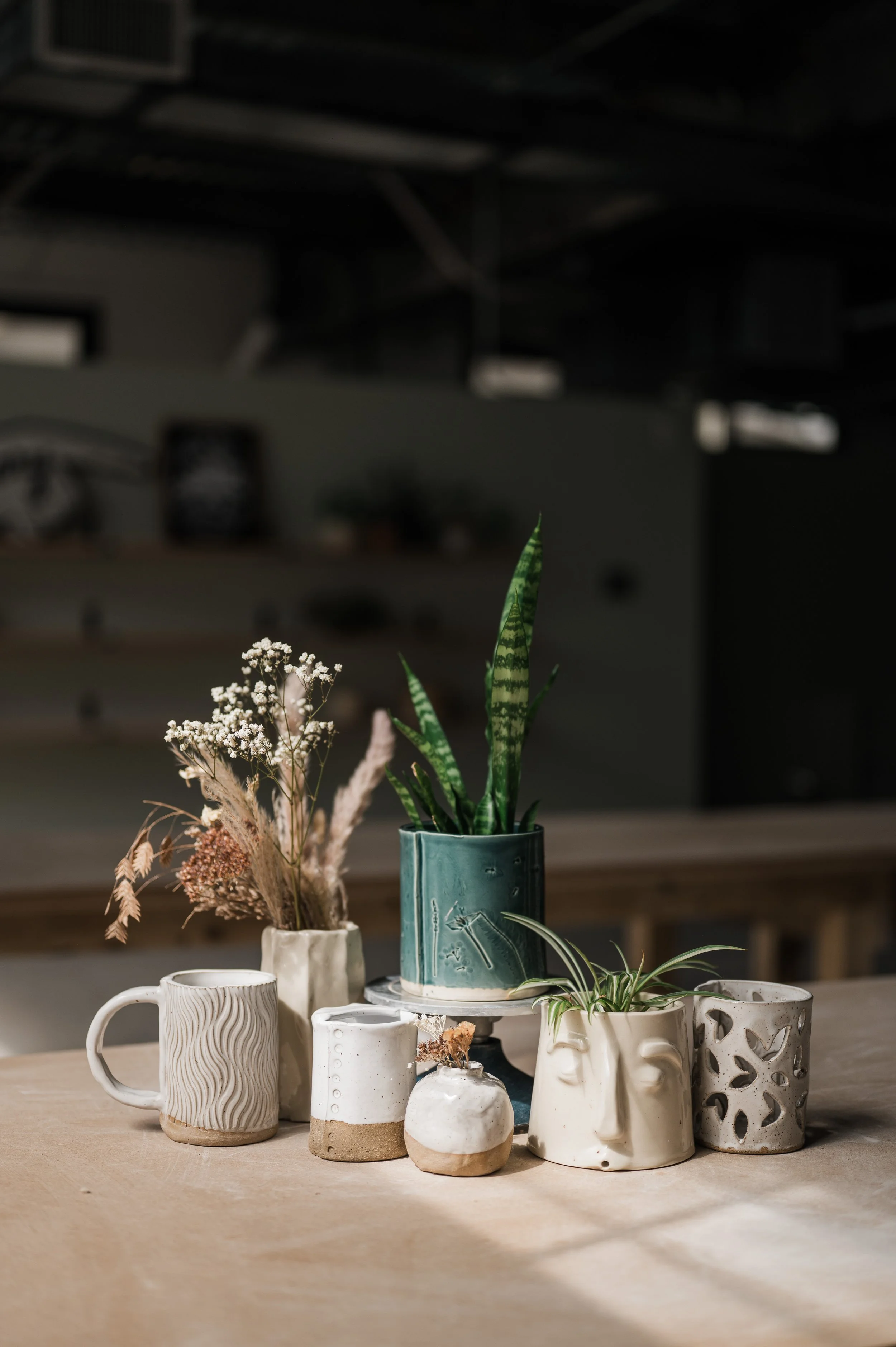 Handbuilding workshop samples including a mug, vase, planter, and luminary that students can make