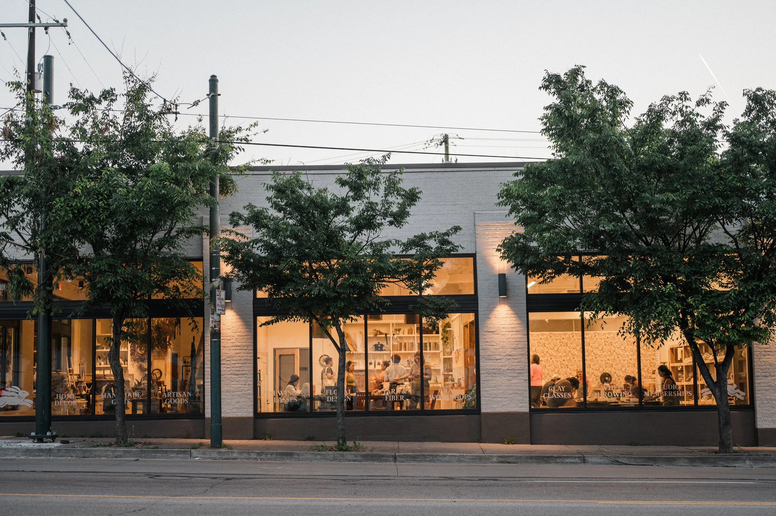 The exterior of MADE Studio & Shop with three windows and people creating inside