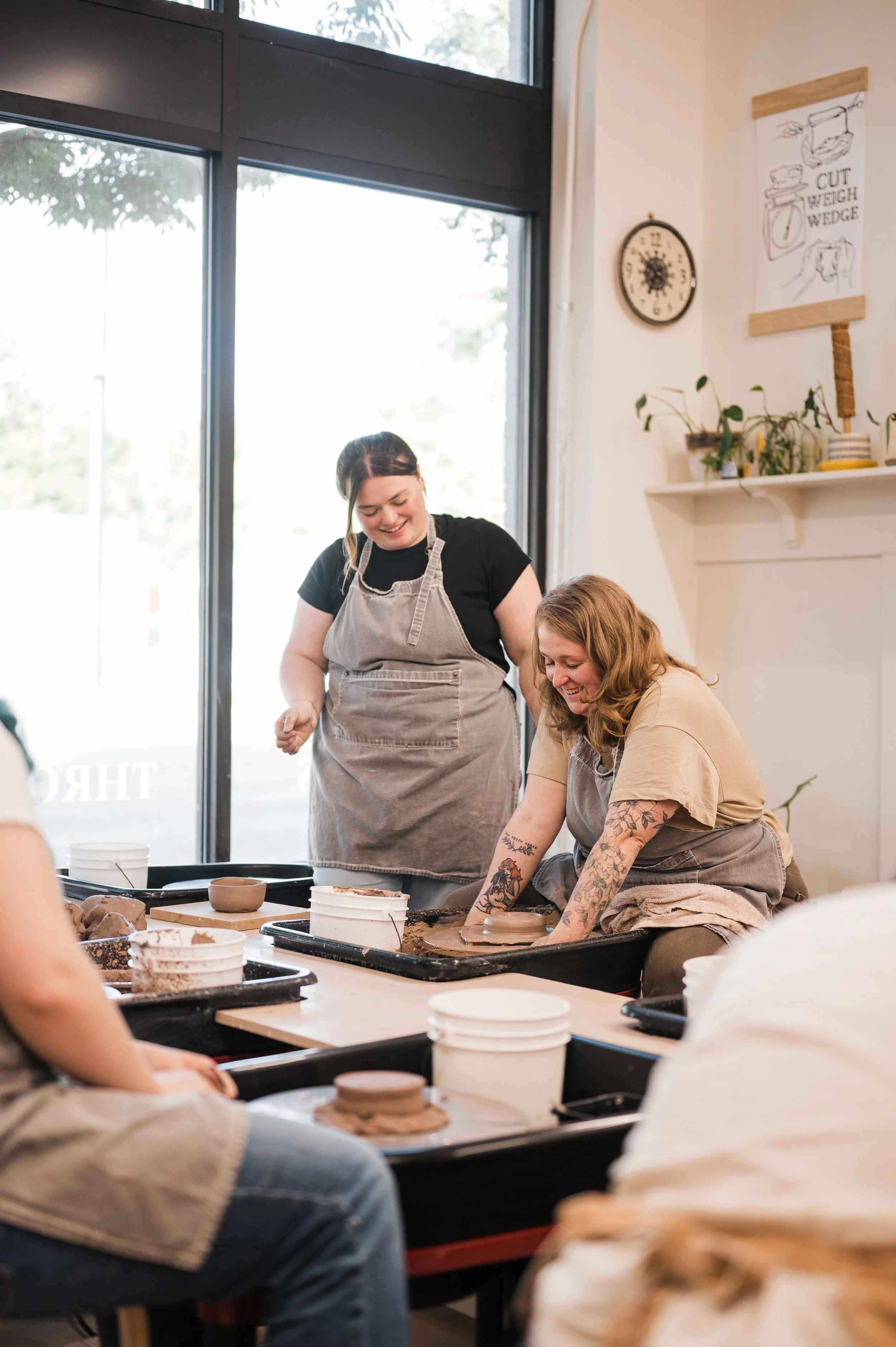Adult throwing pottery with an instructor helping them