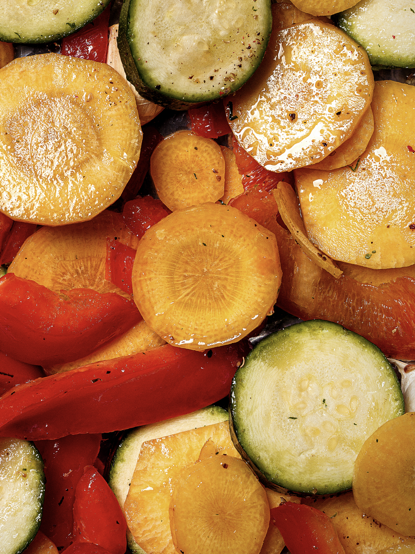 Une assiette de légumes frais, notamment des tranches de concombre, de carotte, de tomate, de poivron et d'oignon, apparemment une salade ou un plat préparé en tranches.