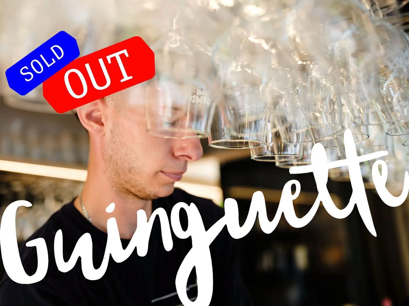 Un homme regardant des verres à vin suspendus près du plafond d'un bar.