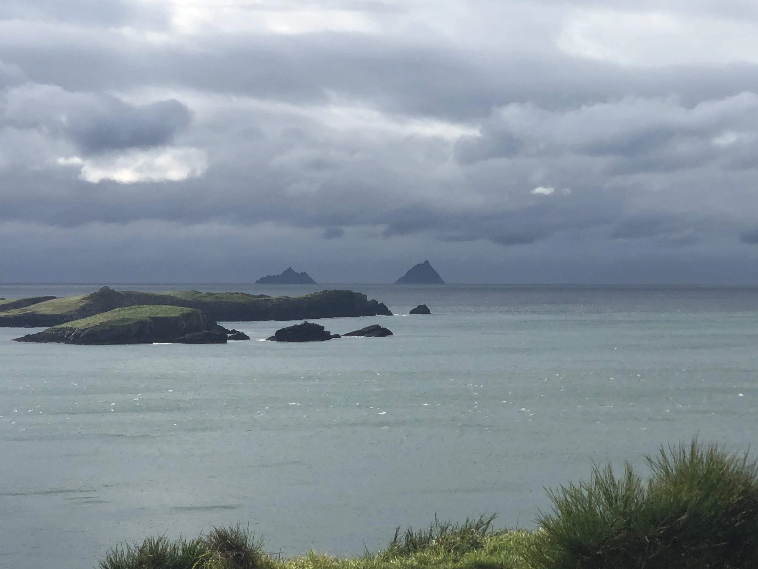A coastal landscape with rocky islands and lush greenery under a cloudy sky.