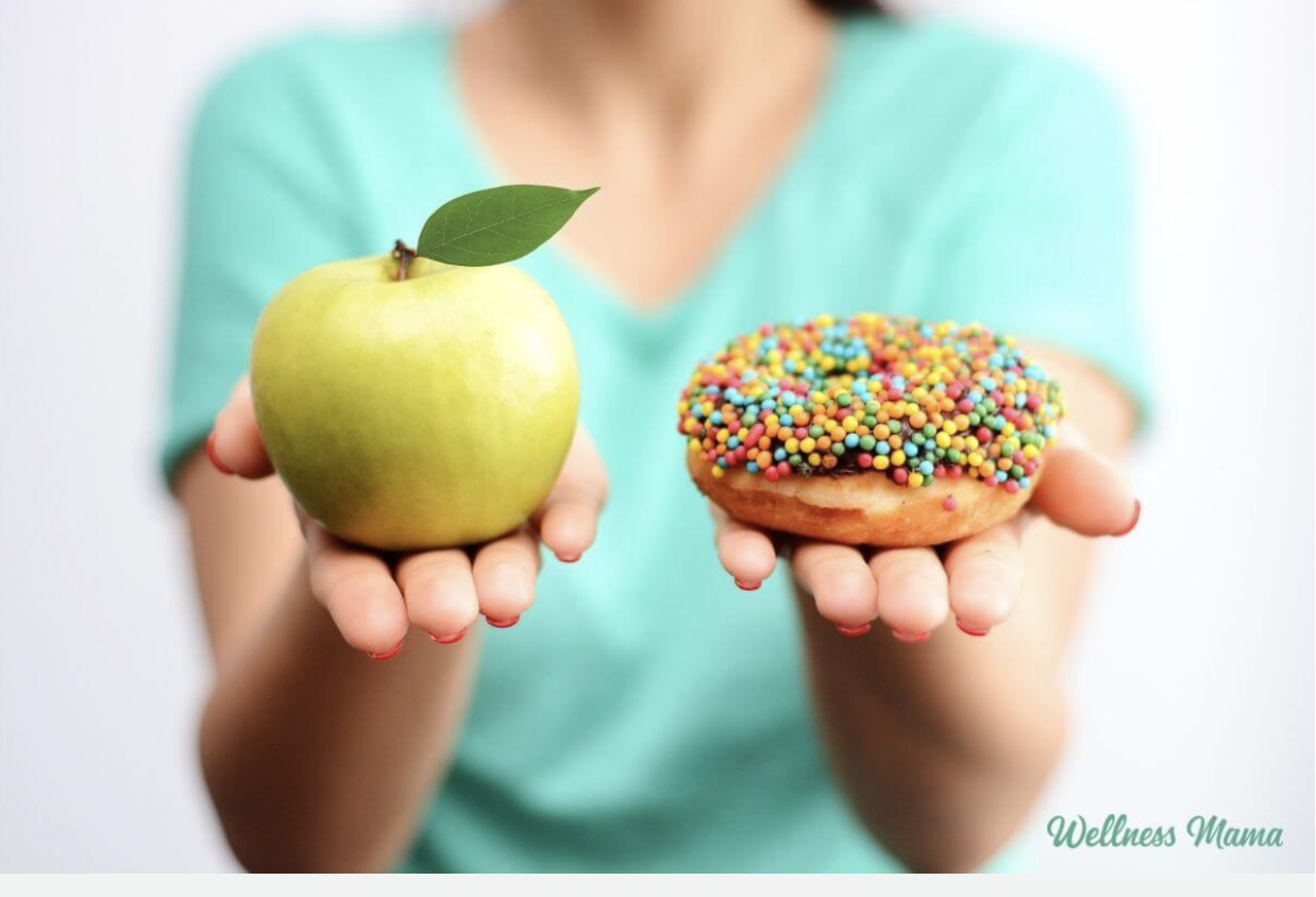 photo of someone holding out an apple and a donut