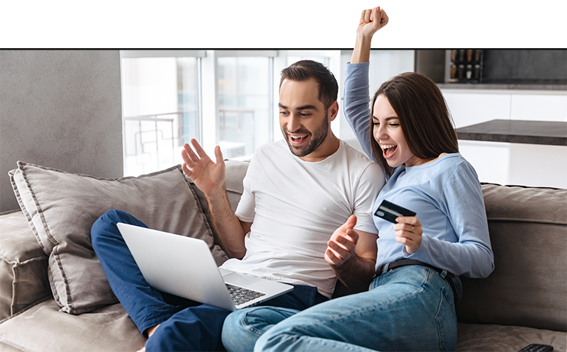 Young couple sitting on the couch looking at Family Living website on laptop