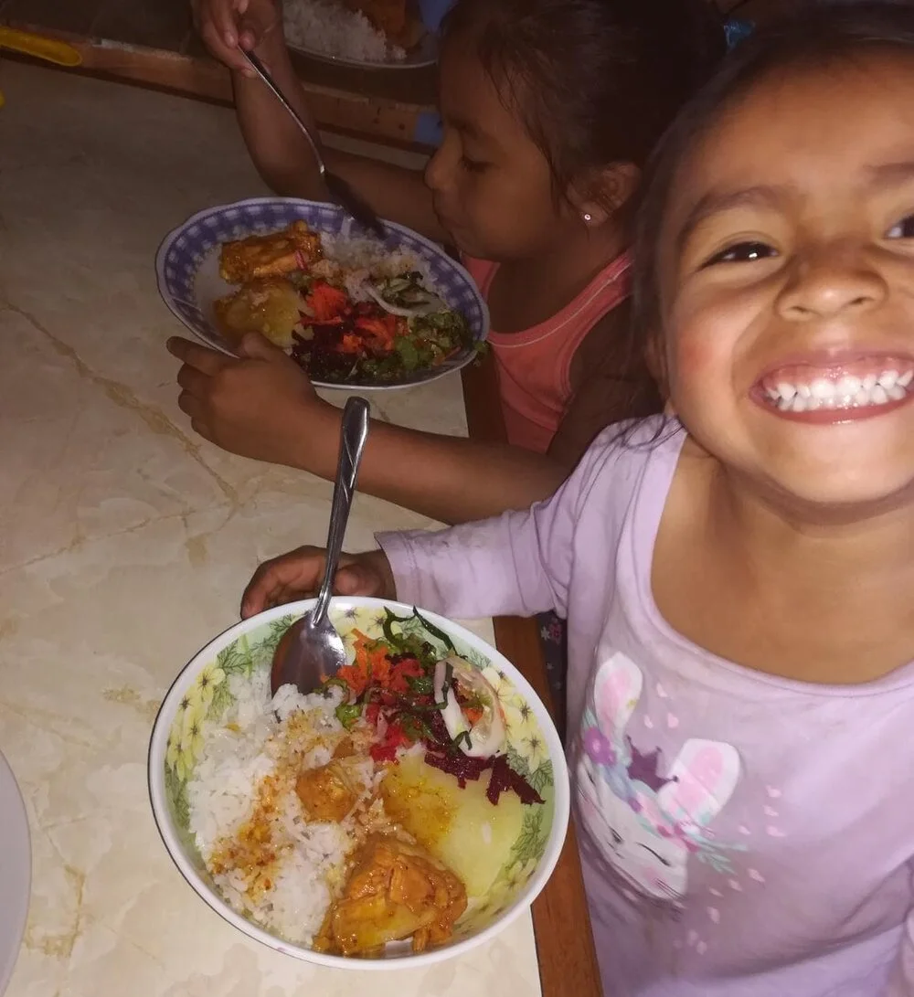Two children with plates of food, one smiling toward the camera.