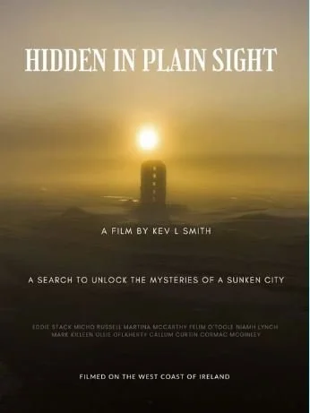 Sunset over misty ocean with a silhouette of an old stone tower in the center. Text reads "Hidden in Plain Sight," a film by Kev L Smith.